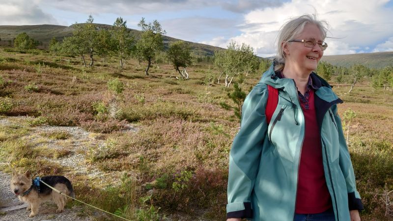 Bild på Astrid Ahlberg i fjäll-landskap med en hund